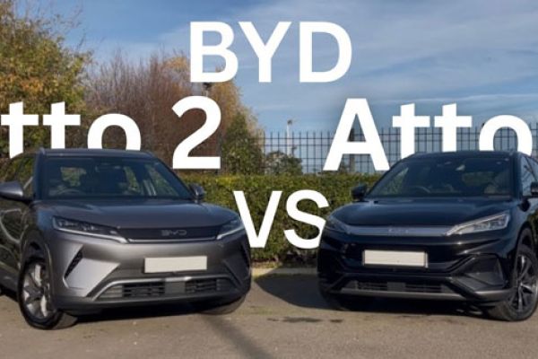 Gray BYD Atto 2 vs black Atto 3 SUVs parked side-by-side; "BYD Atto 2 VS Atto 3" text overlaid, greenery in background.