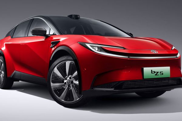 A red Toyota bZ5 electric vehicle with a sleek, futuristic design, showcased against a gray background, highlighting its modern EV aesthetics and branding.