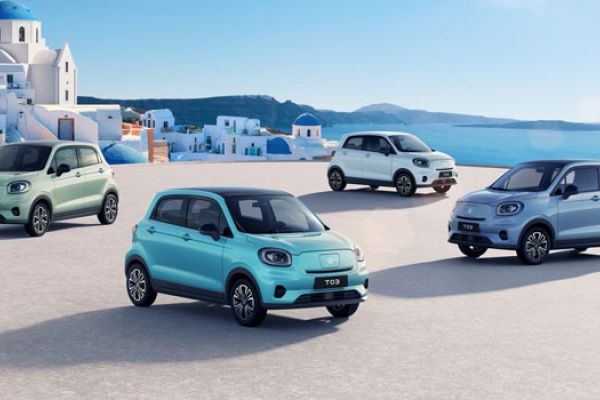 Leapmotor T03 (pastel hues) parked by white Santorini-style buildings and the blue sea.