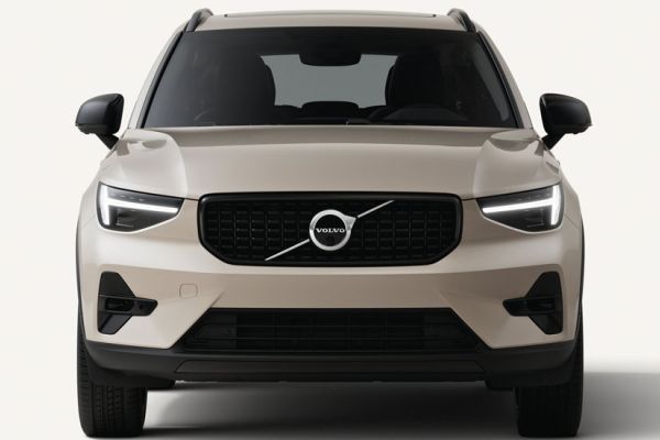 2026 Volvo XC40: front view, illuminated headlights, iconic grille with Volvo logo, plain light background.