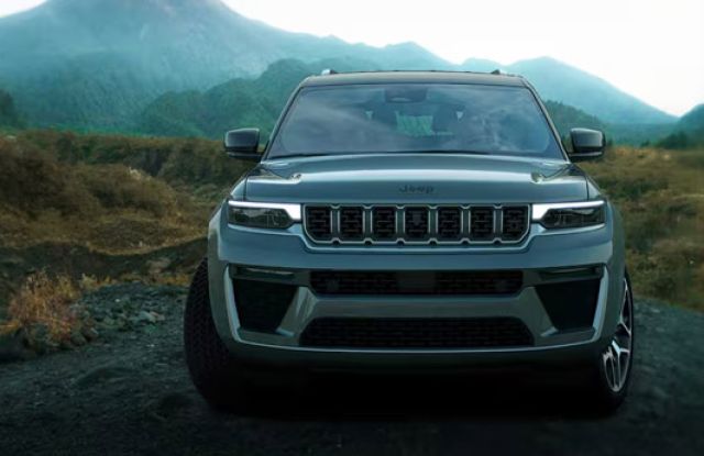 Display A head-on angle of a gray 2026 Jeep Grand Cherokee, traveling on a trail off-road in the mountains