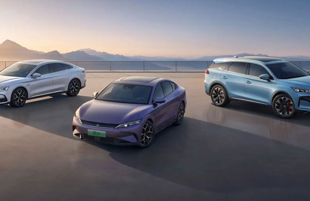 BYD Han and Tang(white, purple, light blue) parked on a terrace, with mountainous sunrise scenery in the background.