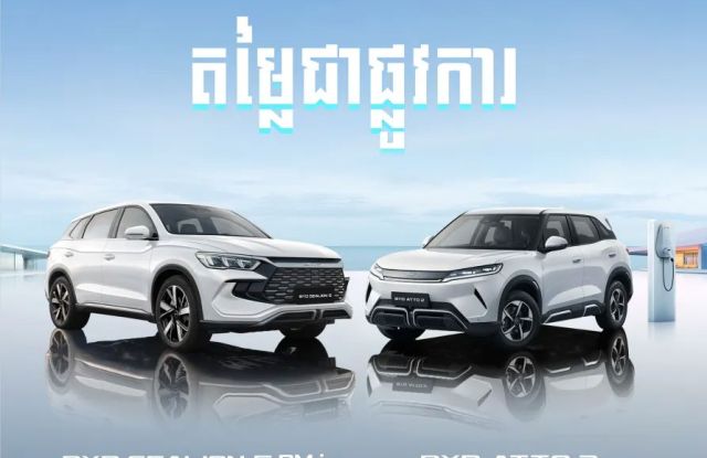Two white BYD SUVs, the Sealion 5 DM-i and Atto 2, displayed against a coastal background with a charging station, under BYD and Harmony Auto branding, with Khmer text highlighting their features.