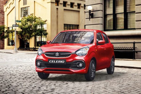 Red Suzuki Celerio parked on a cobblestone street in front of historic city buildings.