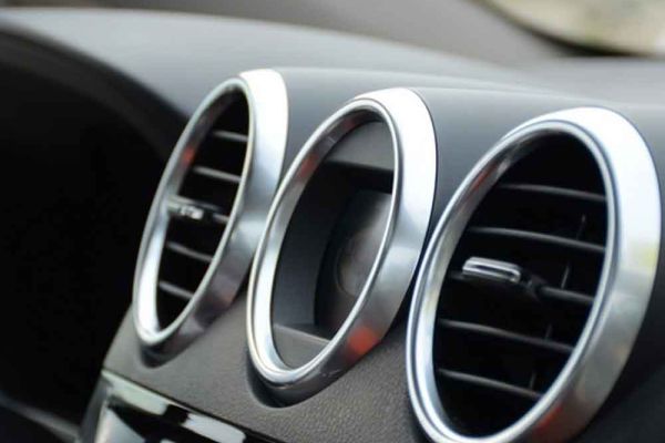 Close - up of car dashboard air vents, silver - rimmed and circular.