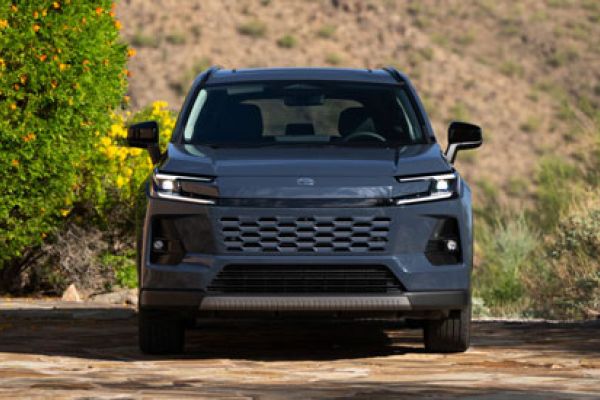 2026 Toyota RAV4 front view: parked on stone surface, surrounded by greenery/desert landscape, sleek grille design.