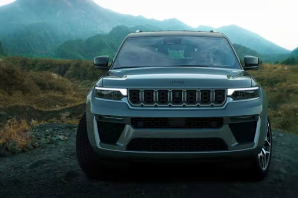 Display A head-on angle of a gray 2026 Jeep Grand Cherokee, traveling on a trail off-road in the mountains