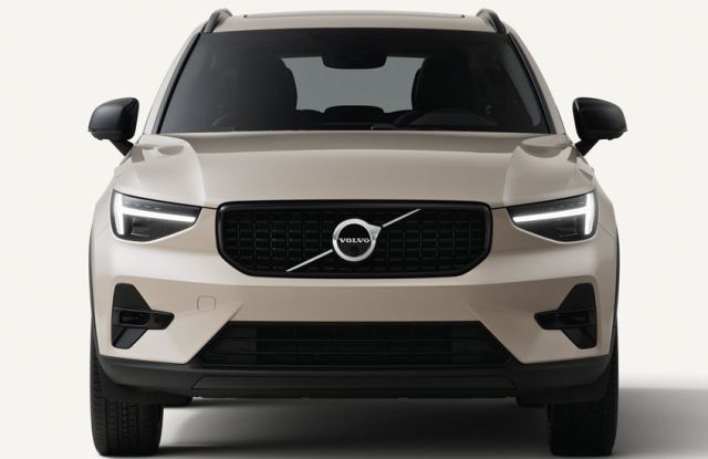 2026 Volvo XC40: front view, illuminated headlights, iconic grille with Volvo logo, plain light background.