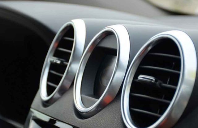 Close - up of car dashboard air vents, silver - rimmed and circular.