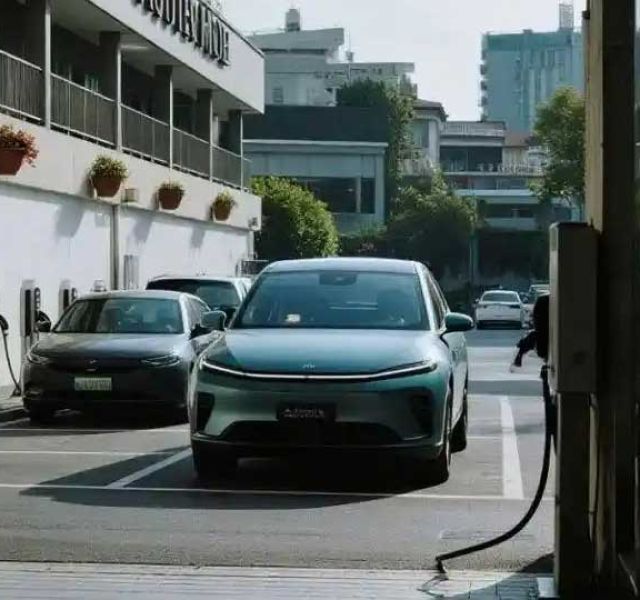 រថយន្តអគ្គិសនីកំពុងសាកថ្មនៅស្ថានីយ៍ដែលមានឆ្នាំងសាកច្រើននៅក្បែរអគារមួយ។