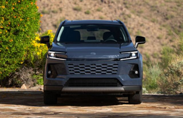 2026 Toyota RAV4 front view: parked on stone surface, surrounded by greenery/desert landscape, sleek grille design.