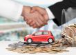 A handshake between two people, a red toy car on a pile of coins, and a jar of coins, symbolizing a car financing or sales agreement.