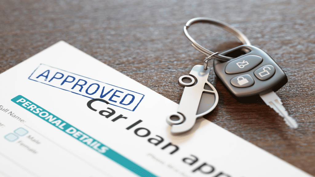 Car keys placed next to an approved car loan document on a wooden surface.