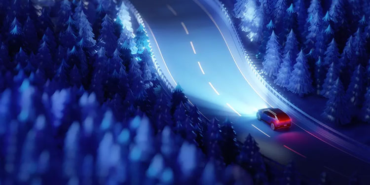 2025 Volkswagen ID. Buzz drives on a curving night road through a snowy, blue-lit forest, with headlight beams illuminating the way.