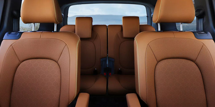 Rich brown leather-like seats in a 2025 Volkswagen ID. Buzz’s rear cabin; scenic water and hills visible through the back window.