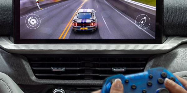 A passenger playing a racing game on the center display of a parked 2026 Ford Explorer SUV