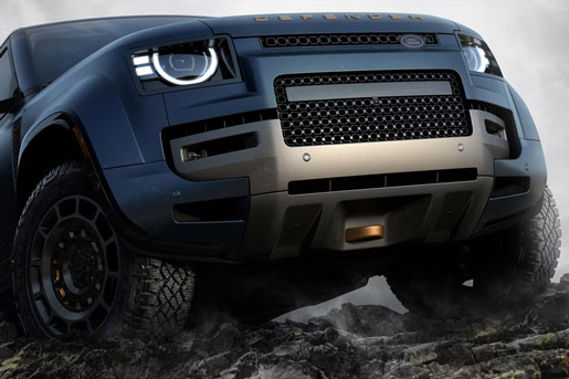 Low-angle front view of a blue Land Rover Defender on rocky terrain