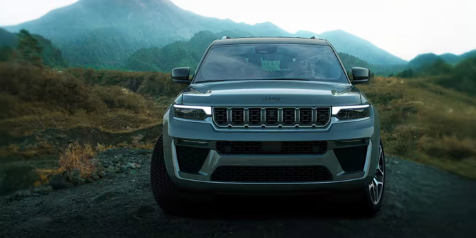 Display A head-on angle of a gray 2026 Jeep Grand Cherokee, traveling on a trail off-road in the mountains