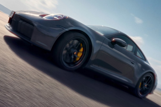 Porsche 911 Carrera GTS in Slate Grey Neo driving on a road. Front and side views