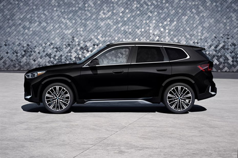Side view of an 2026 BMW X1 parked infront of a grey tiled wall.
