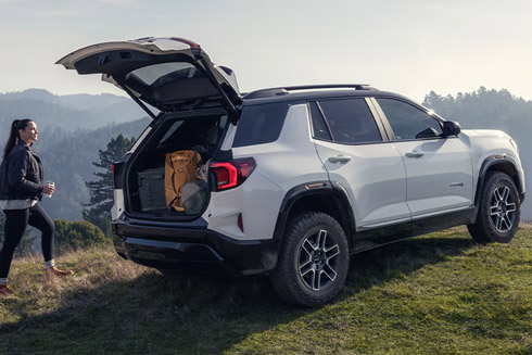 Rear View of the Open Tailgate on the 2026 GMC Terrain AT4 Small Off-Road SUV While A Person Unloads the Cargo