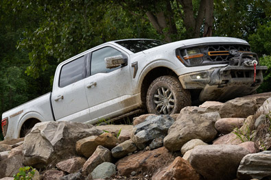 2026 Ford F-150 Tremor pickup in Oxford White being driven up a rocky slope